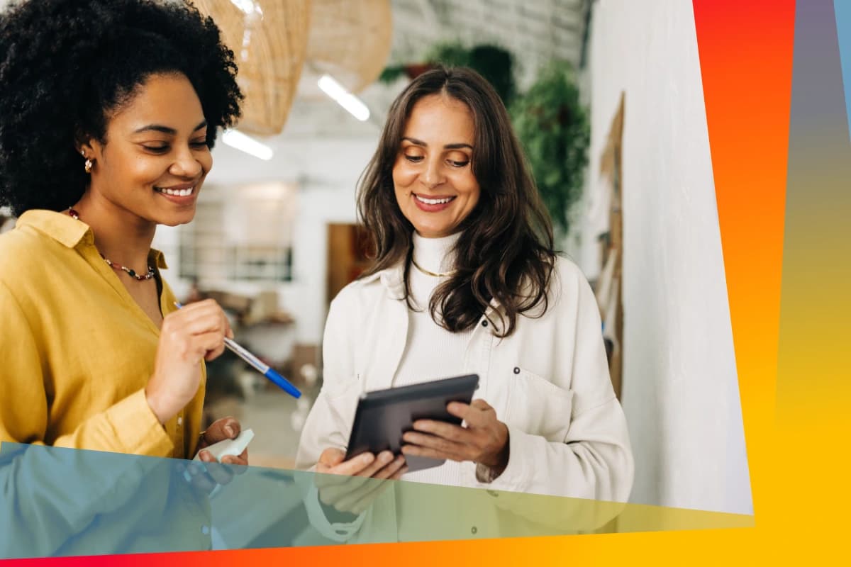 Två kvinnor som ler och tittar på en surfplatta